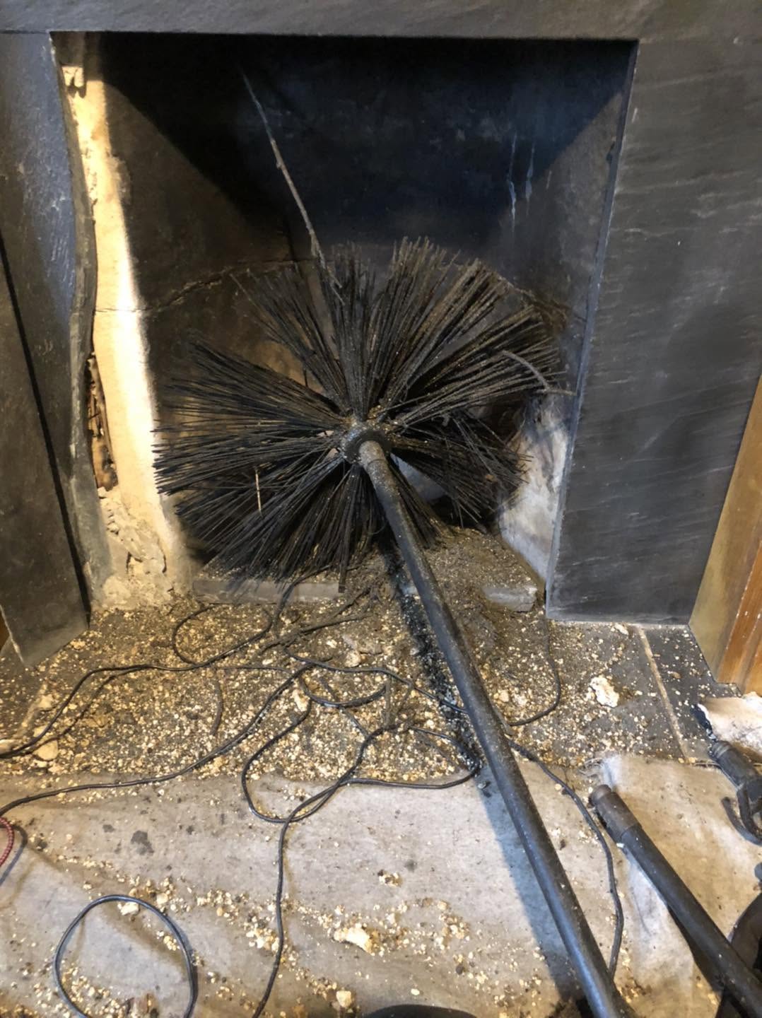 Sweep's brush and rods in a fireplace, mid sweep, with the soot on a dust sheet