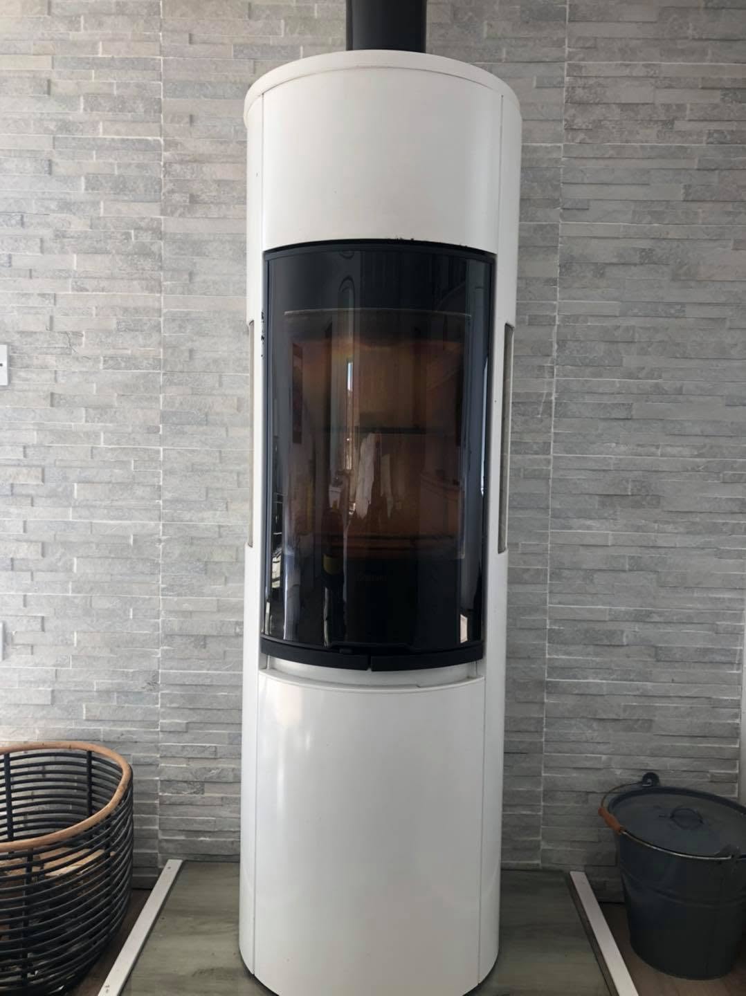 Tall white contemporary stove against a stone-effect wall