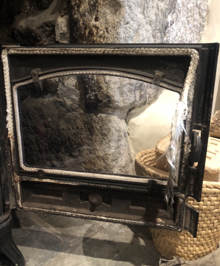 Stove door open showing the fire chamber against granite stonework