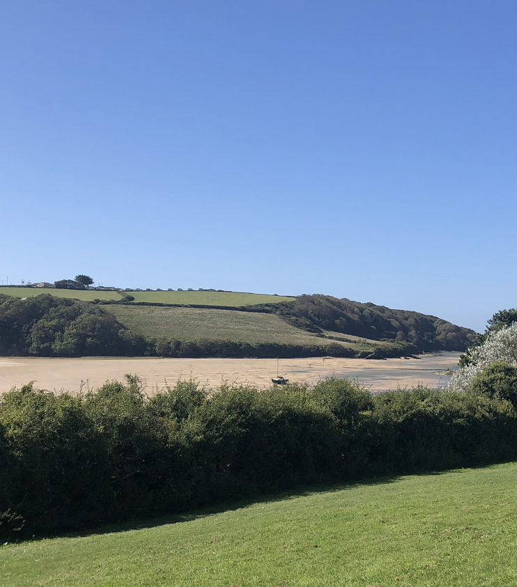 A Cornish estuary and beach under a clear sky