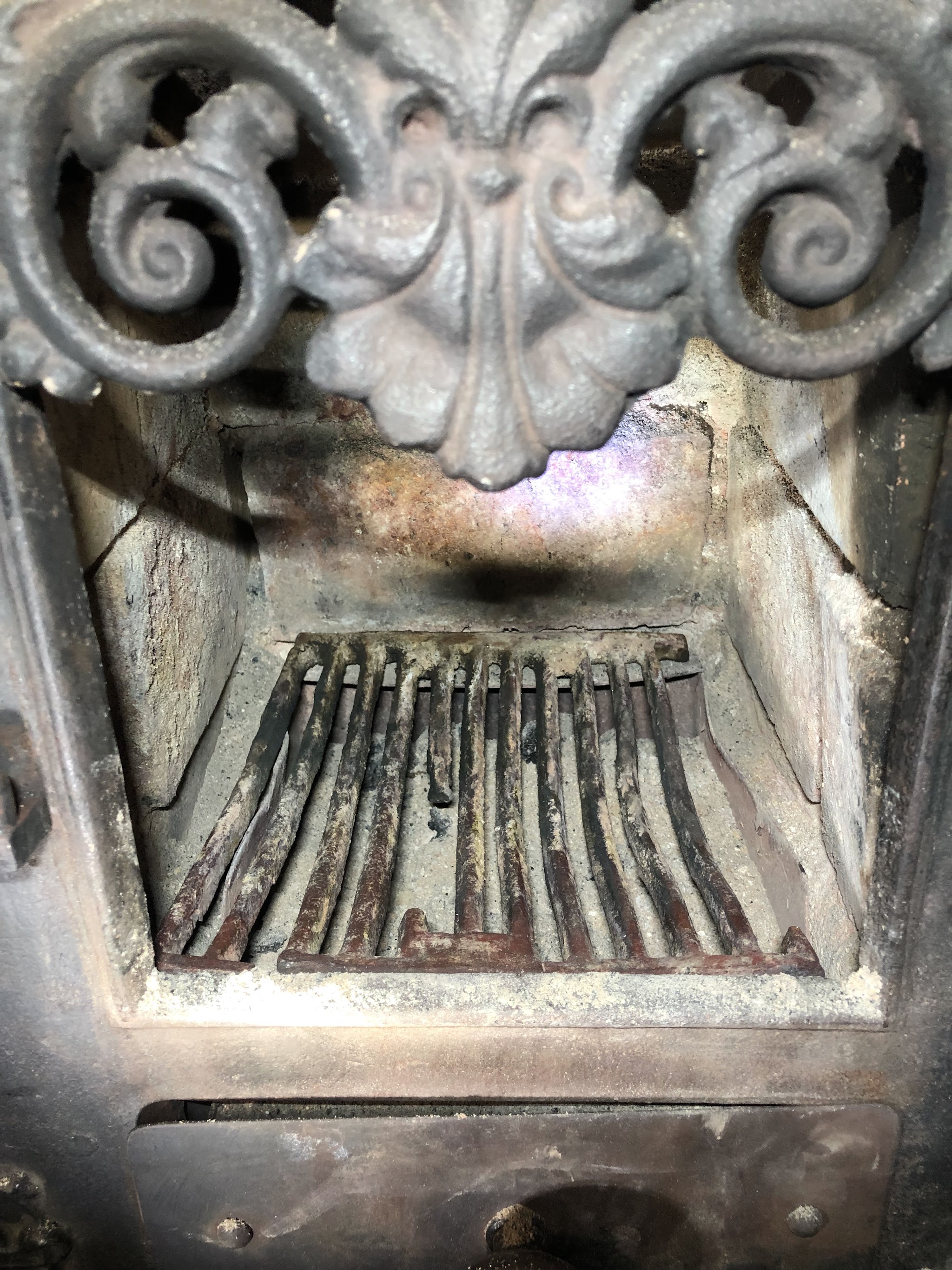 Cast-iron stove grate under an ornate canopy